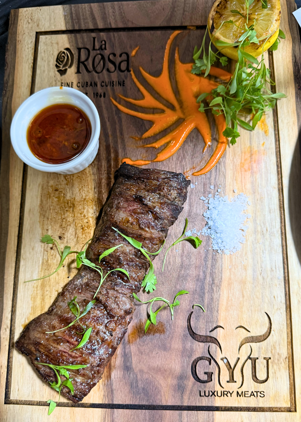 Steak on a wooden cutting board with 'La Rosa' and 'GYU Luxury Meats' branding.